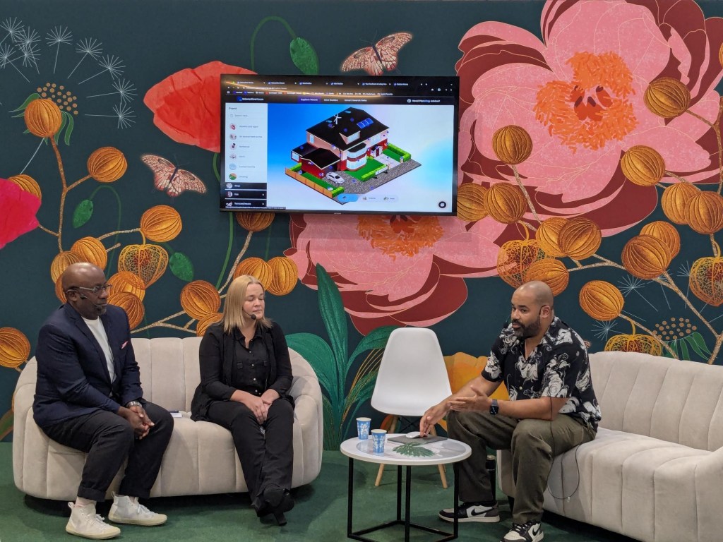 TerraQuest colleagues seated on stage at Grand Designs Live demonstrating the Interactive House.