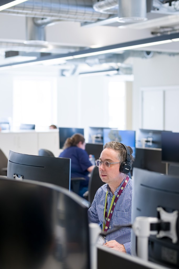 Staff member wearing headphones working at a computer in the TerraQuest office.