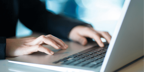 Hands typing at laptop
