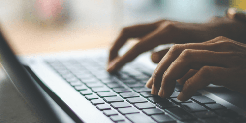 Hands typing at a laptop keyboard