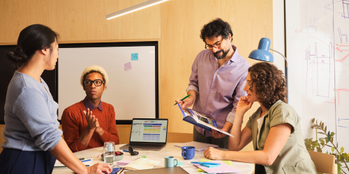 Team working in office with whiteboards, postit notes, laptop