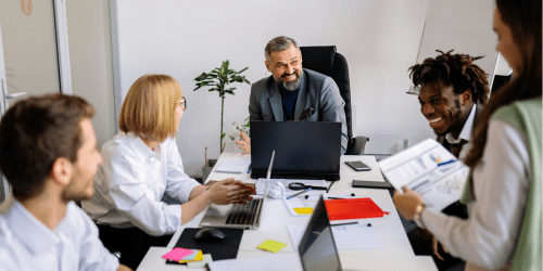 Office team having a meeting around a desk with documents and laptops