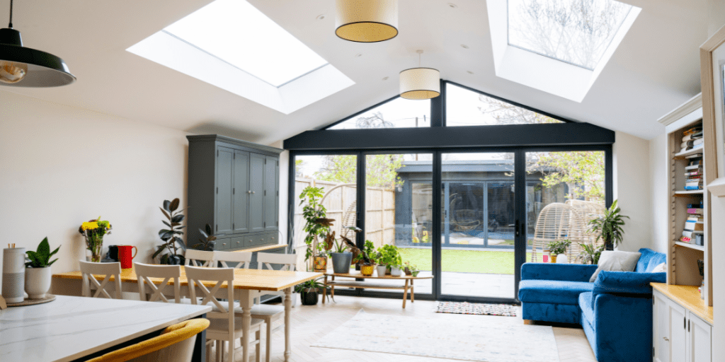 Modern property extension with wide glass doors opening onto a garden, featuring a warm wooden interior and plants.