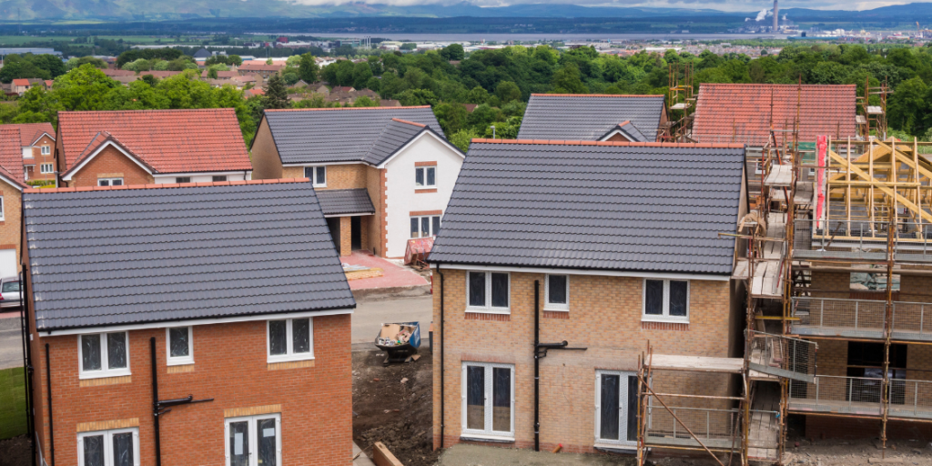 New-build red and white brick houses being constructed on a residential housing estate.