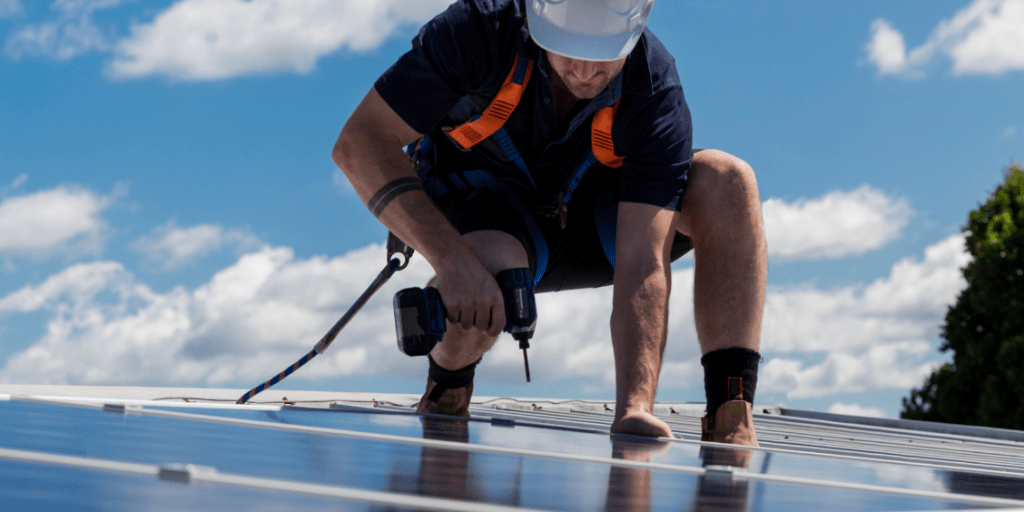 Man installing solar panels against a blue cloudy sky
