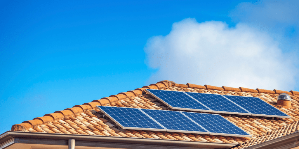 Solar panels installed on a domestic rooftop with a blue sky behind